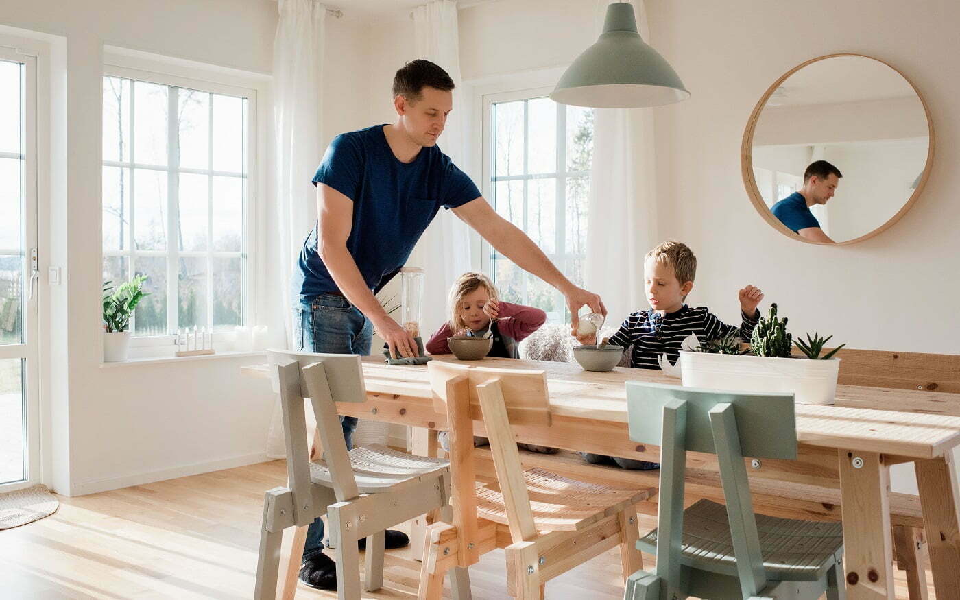 Isä kattaa lounasta kahdelle lapselle ja he ovat juuri aloittamassa ruokailun kauniissa kodissaan puisen pöydän äärellä Retta