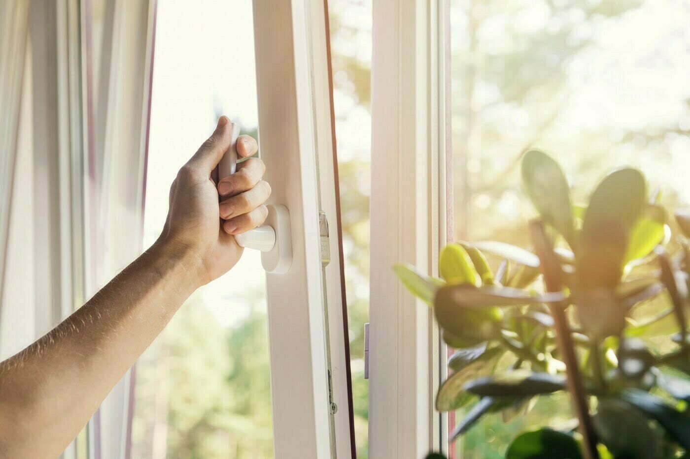 Asunnon viilennys Käsi avaa ikkunaa ja auringonvalo tulvii sisään.