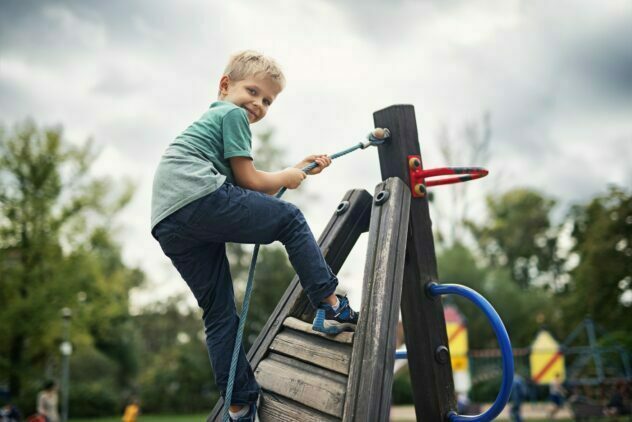 Leikkipaikka taloyhtiössä. Retta Isännöinti. Pieni poika leikkii lasten leikkipaikalla ja hymyilee kameralle.